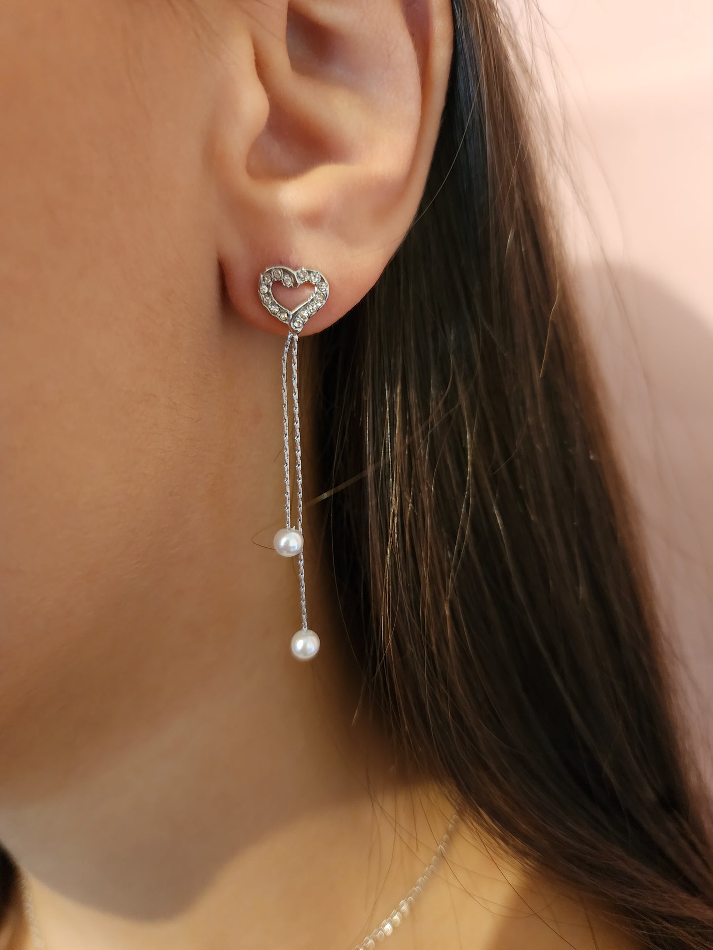 Boucles d'Oreilles Jada en acier inoxydable argenté avec cœur et perles suspendues, portées sur une oreille