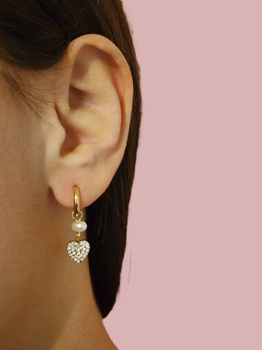 Boucles d'Oreilles Sara en acier inoxydable doré ou argenté avec perle et cœur scintillant, portées sur une oreille