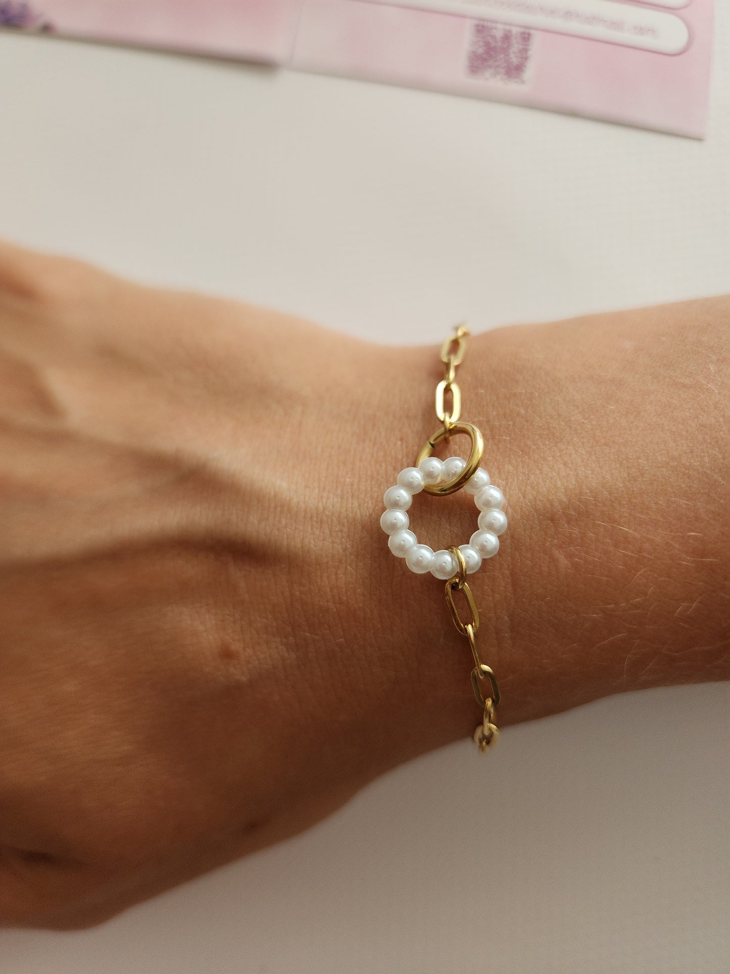 Bracelet Alana en acier inoxydable doré avec cercle de perles blanches, porté sur un poignet