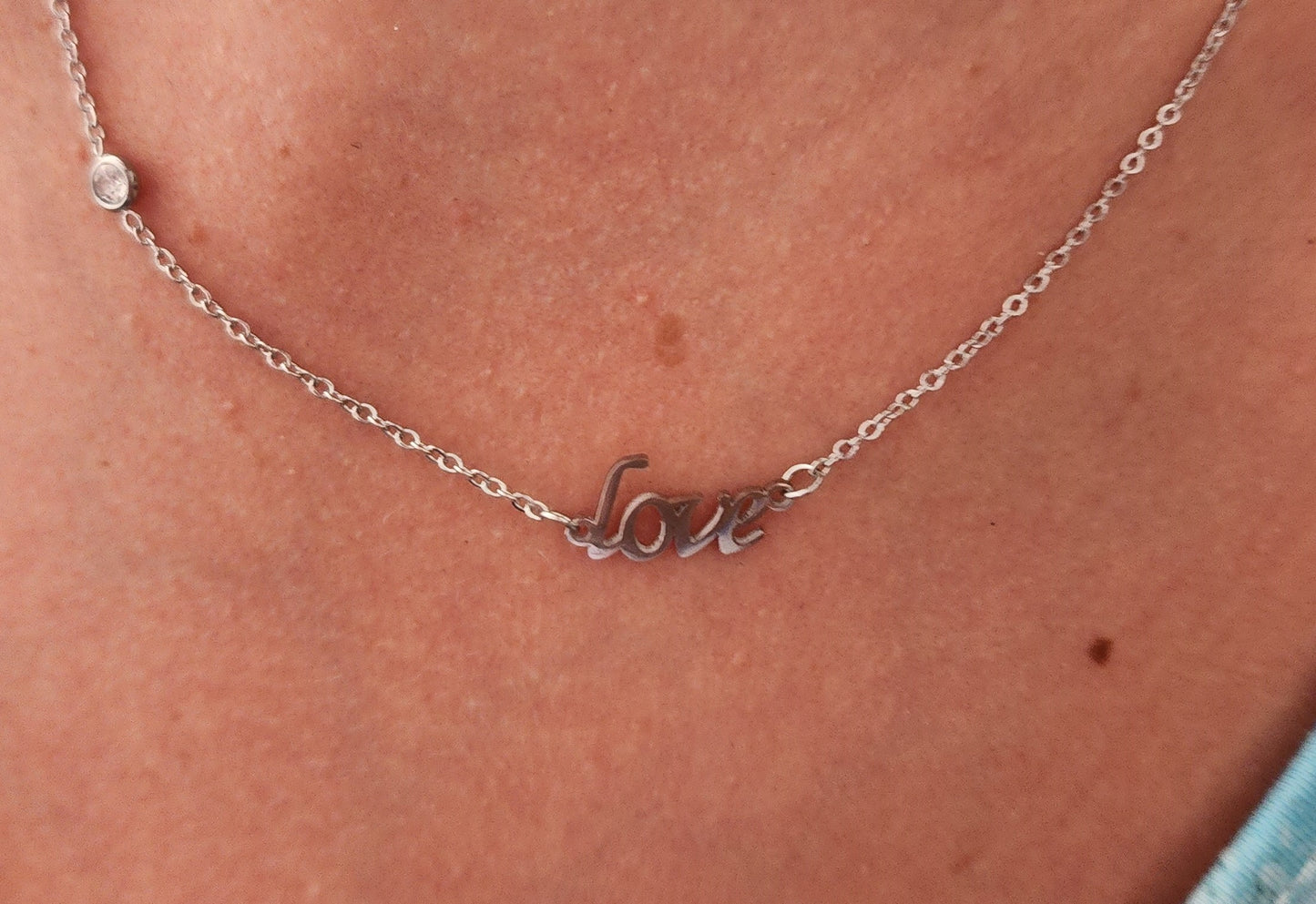 Détail du motif 'Love' du Collier Cordélia en acier inoxydable argenté.