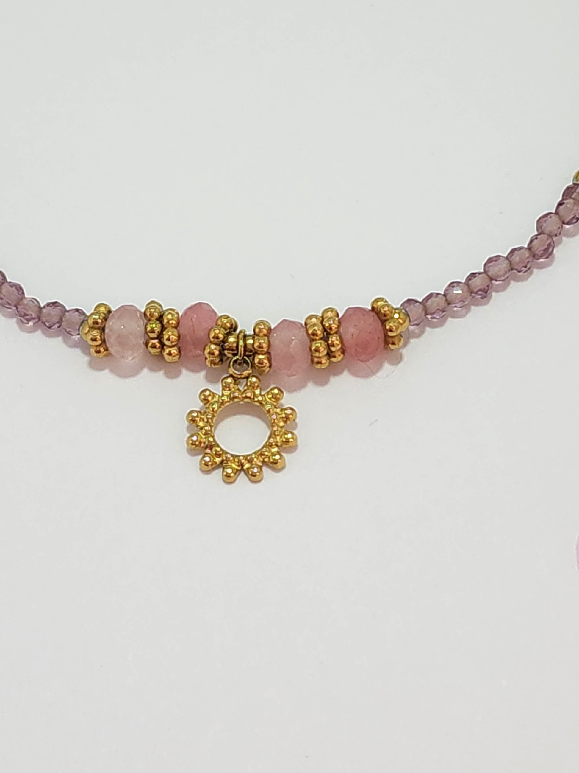 Détail des pierres mauves et pendentif soleil du bracelet Jana en acier inoxydable doré