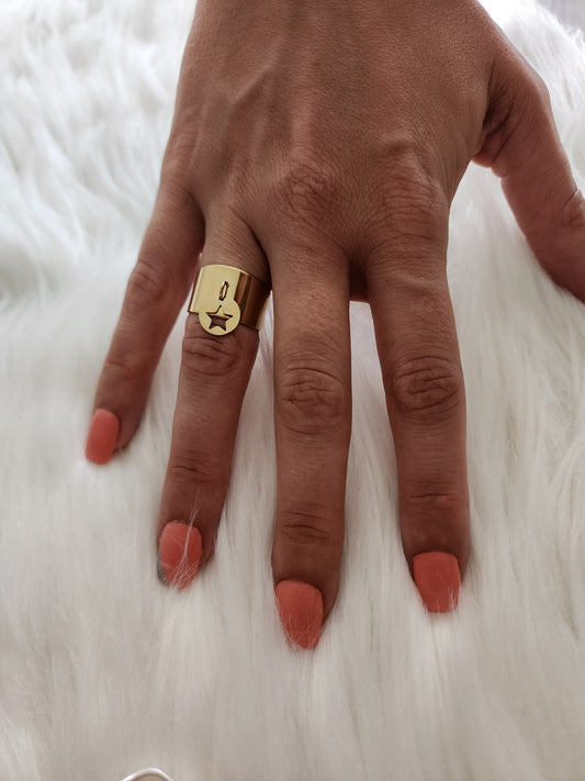 Bague Léa en acier inoxydable doré avec étoile gravée et charm suspendu, portée sur une main.