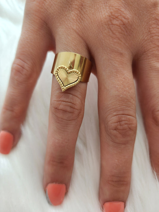 Bague Léna en acier inoxydable doré avec médaillon cœur texturé, portée sur une main.