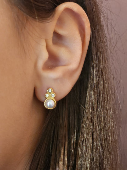 Boucles d'Oreilles Andréa en acier inoxydable doré avec strass brillants et perle élégante, portées sur une oreille