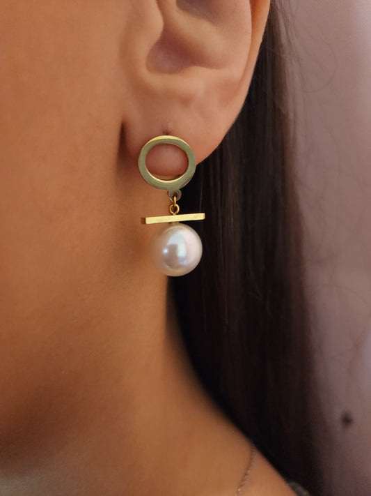 Boucles d'Oreilles Mélia en acier inoxydable doré avec anneau ajouré et perle suspendue, portées sur une oreille