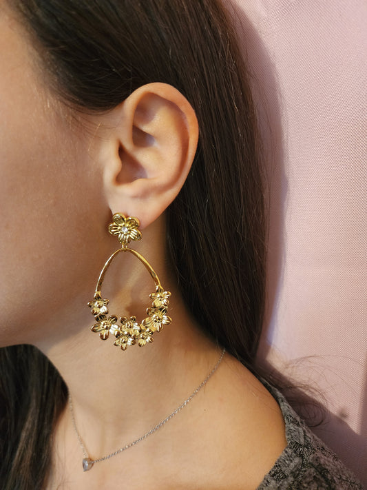 Boucles d'Oreilles Shana en acier inoxydable doré avec fleurs délicates, portées sur une oreille