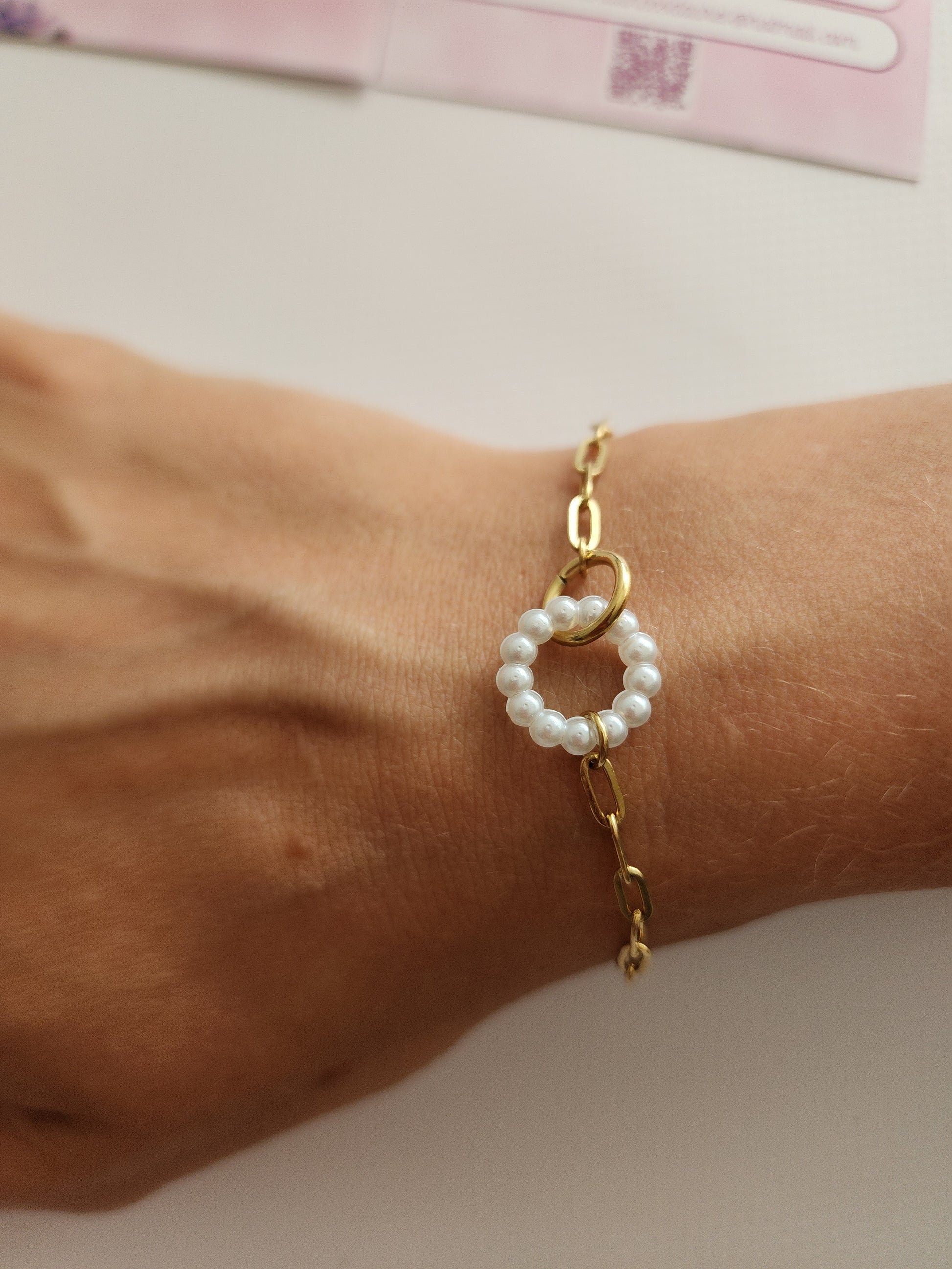 Bracelet Alana en acier inoxydable doré avec cercle de perles blanches, porté sur un poignet
