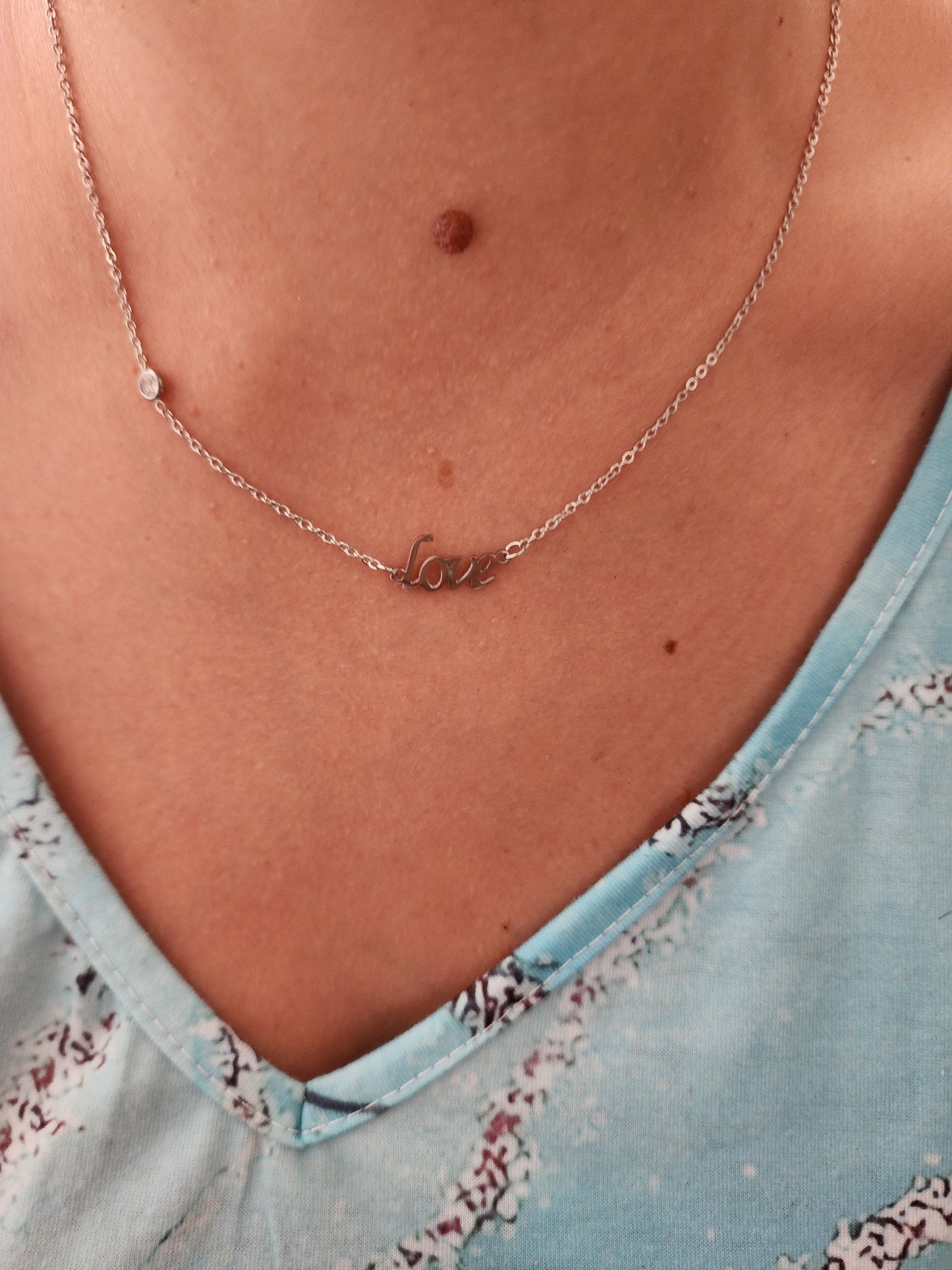 Collier Cordélia en acier inoxydable argenté avec motif 'Love', porté sur un cou