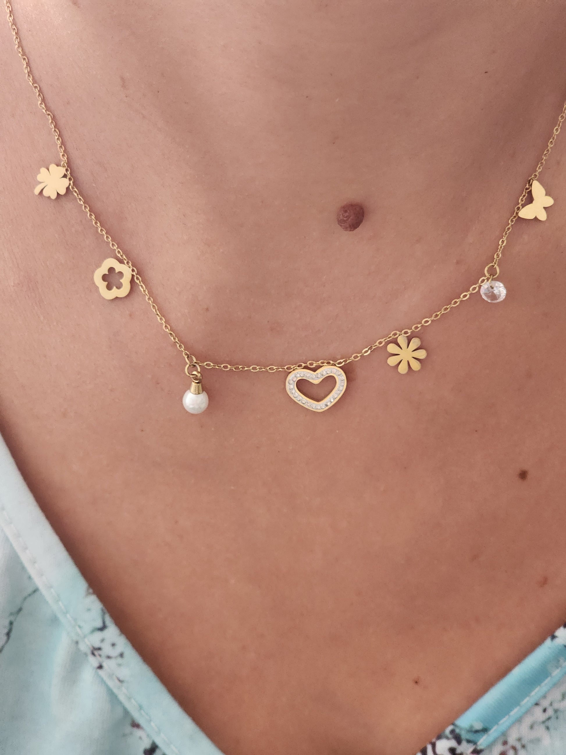 Collier Héléna en acier inoxydable doré avec breloques cœurs, fleurs et strass, porté sur un cou