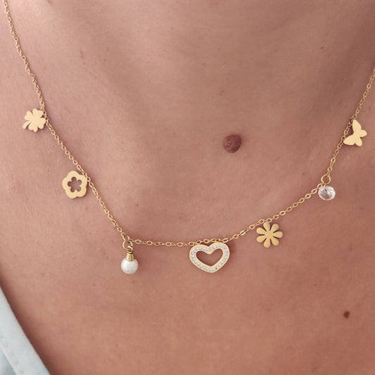Collier Héléna en acier inoxydable doré avec breloques cœurs, fleurs et strass, porté sur un cou