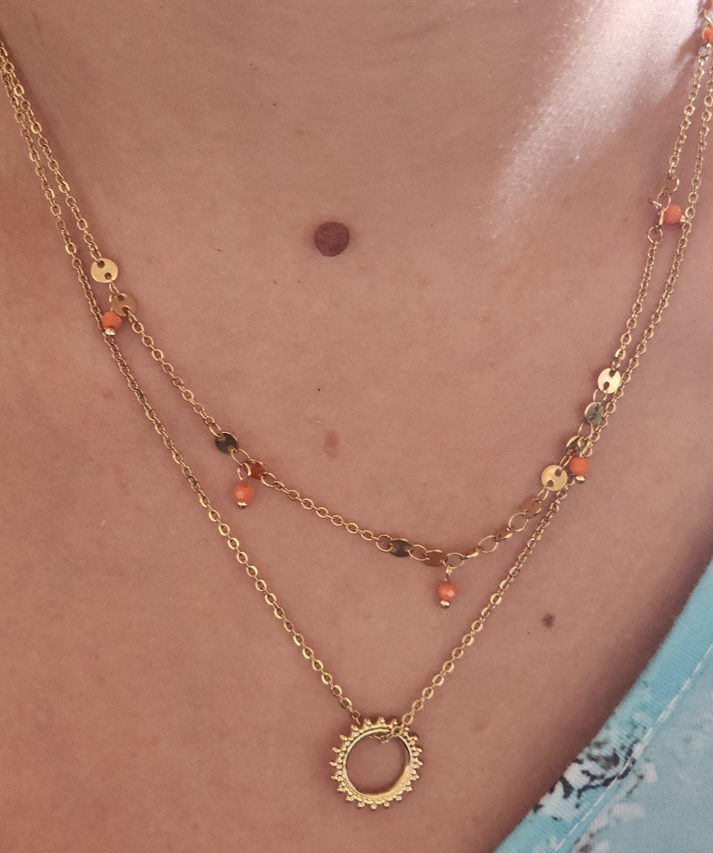 Collier Julia en acier inoxydable doré à double rang avec pendentif soleil, porté sur un cou.