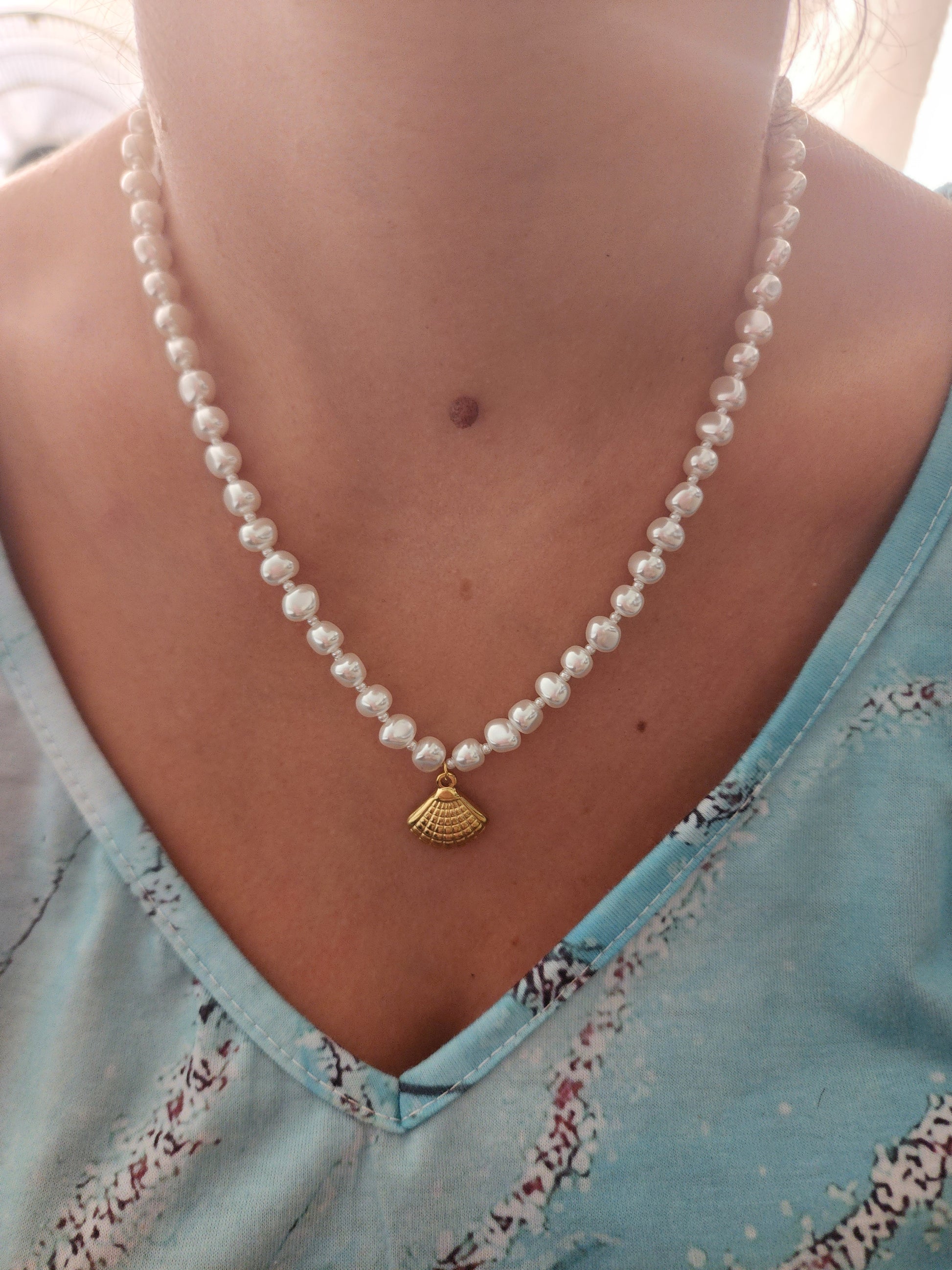 Collier Klervia en acier inoxydable doré avec perles et pendentif coquillage, porté sur un cou.